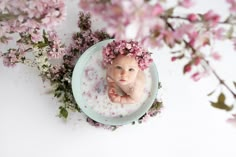 a baby is sitting in a tub with pink flowers on the head and body, surrounded by water