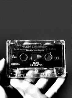 a hand holding an old fashioned cassette player in front of a black and white background