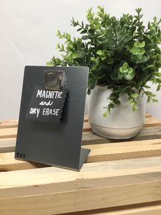 there is a sign that says magnetic and dry erase on it next to a potted plant