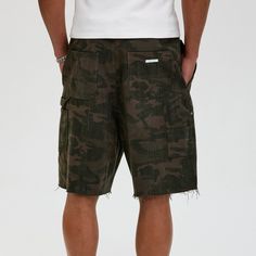 The Frayed Double-Knee Camo Cargo Shorts masterfully blend military elements with street style. These slightly oversized shorts feature an all-over camouflage print and a durable double-knee design for added toughness. The frayed hem adds an edgy touch, while the back pocket is adorned with a metal logo badge for a distinctive look. Crafted from premium 100% cotton fabric (370g/m²), these shorts ensure both comfort and durability, making them perfect for any urban adventure. All-over camouflage Combat Cargo Style Bottoms For Summer, Summer Combat Cargo Style Bottoms, Summer Combat Cargo Bottoms, Summer Combat Cotton Bottoms, Camouflage Cotton Cargo Shorts With Side Pockets, Cargo Style Knee-length Shorts For Streetwear, Military Camouflage Cotton Shorts, Camouflage Military Cotton Shorts, Knee-length Cargo Shorts For Streetwear