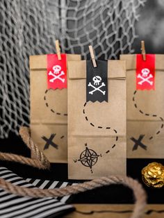 two brown paper bags with pirate designs on them and some gold foil in the background