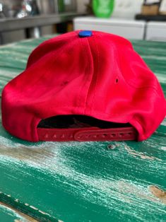 a red hat sitting on top of a green wooden table next to a white counter