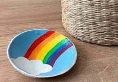 a wooden bowl with a rainbow painted on the side sitting next to a wicker basket