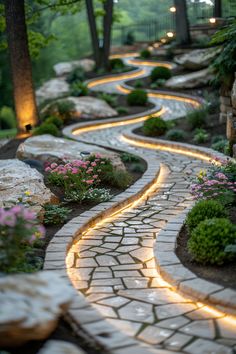 a stone path with lights in the middle and flowers on both sides, surrounded by trees