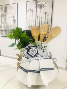 towels and utensils are sitting in a basket on a counter top with palm trees behind them