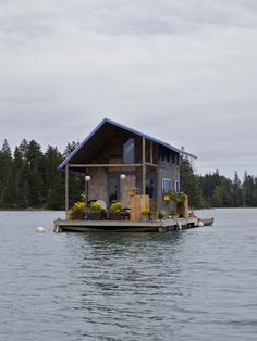 a floating house on the water with trees in the background