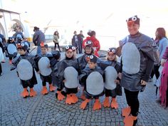 a group of people in penguin costumes standing next to each other on a cobblestone walkway