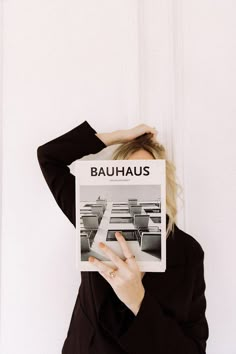 a woman holding up a magazine with the word bauhus on it's face