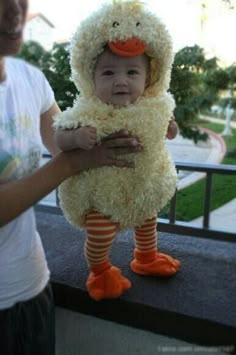 a baby in a duck costume being held by someone