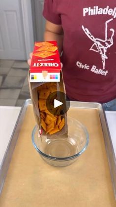 a box of cheetos sitting on top of a counter next to a person