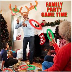 a man is playing with his family in front of the christmas tree and holding frisbees