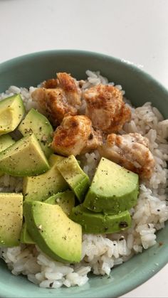 a bowl filled with rice, avocado and chicken on top of it's side