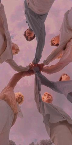 four people are holding their ties in the shape of a circle while looking up into the sky