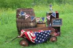 an old wagon decorated with american flags sits in the grass next to some liquor bottles