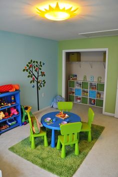 a child's playroom with green and blue chairs, table and bookshelves