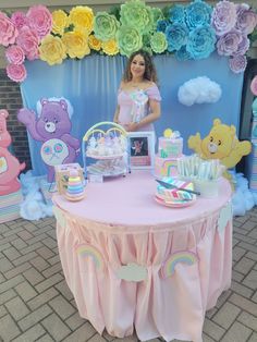 a woman standing in front of a pink table with decorations on it and teddy bears