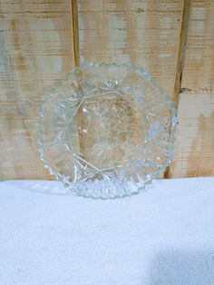 a clear glass bowl sitting on top of a white cloth covered table next to a wooden wall