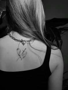 the back of a woman's neck with a heart and cross tattoo on it