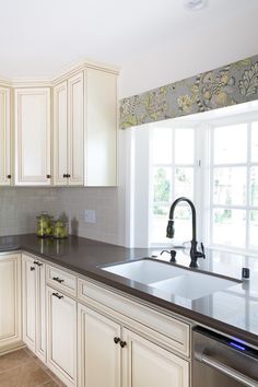 a kitchen with white cabinets and black counter tops, along with a dishwasher