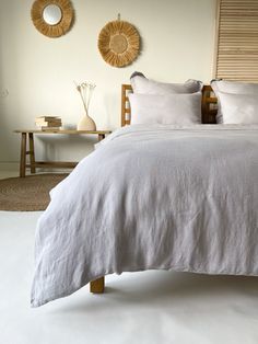 a bed with white linens and pillows in a small room next to two round mirrors