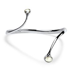 Discover the elegance of the Sterling Silver Georg Jensen Moonstone Bypass Cuff Bracelet. This exquisite piece features two stunning oval moonstone cabochons, measuring 6x4mm and 8x6mm, beautifully bezel set at each end of the cuff. The high-polish finish enhances the bracelet’s sophisticated design, while the inner diameter measures 2.75" at its widest point, ensuring a comfortable fit. Stamped with "GEORGE JENSEN 925 DENMARK 924," this bracelet is a testament to timeless craftsmanship. Complete with a box, it makes for a perfect gift or a luxurious addition to your jewelry collection. Elevate your style with this enchanting piece. Georg Jensen Jewelry, Georg Jensen, Bezel Setting, Cuff Bracelet, Moonstone, Jewelry Collection, Cuff, Perfect Gift, Sterling Silver