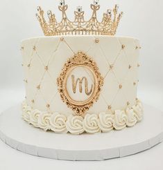 a white cake with gold decorations and a crown on top