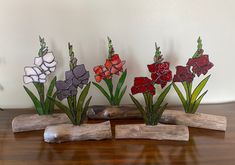 three wooden sticks with flowers in them sitting on a table