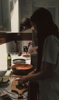 two people preparing food in a kitchen on top of a counter next to each other