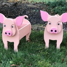 two pink pig shaped chairs sitting in the grass next to each other on top of green grass