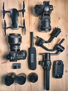 many different types of cameras and accessories laid out on a wooden surface