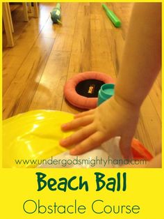 a child's hand reaching for a beach ball obstacle course