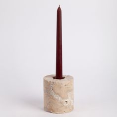 a single candle is placed in a marble container with a red wax stick sticking out of it