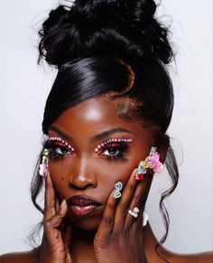 a woman with bright makeup and flowers in her hair holding her hands to her face