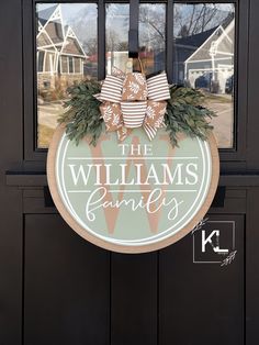 the williams family door hanger is decorated with greenery and bows on an entry door