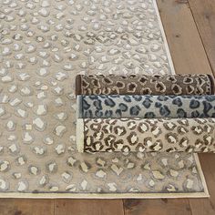 three rugs with different animal prints on them in various sizes and colors, sitting on a wooden floor