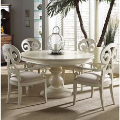 a white dining table and chairs with palm trees in the backgroung area