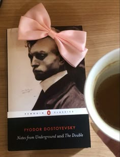 a book with a pink bow on it next to a cup of coffee