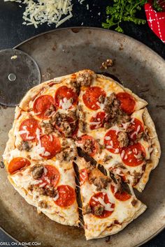 a pizza sitting on top of a metal pan covered in cheese and pepperoni slices