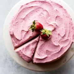 a cake with pink frosting and a strawberry on top is shown in this image