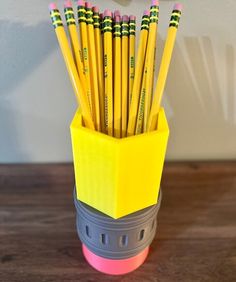 a cup filled with yellow pencils sitting on top of a wooden table