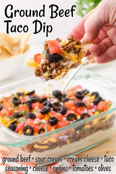 ground beef taco dip recipe in a glass casserole dish with black olives and tomatoes