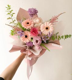 a bouquet of flowers is being held by someone's hand on a white background