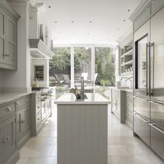 a large kitchen with white cabinets and stainless steel appliances in front of an open window