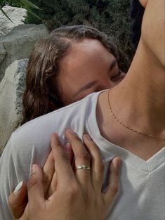 a man and woman embracing each other in front of some rocks