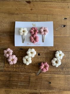 four crocheted flower clips on top of a wooden table next to a card