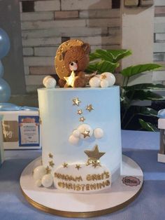 a teddy bear sitting on top of a white and blue cake with gold stars around it