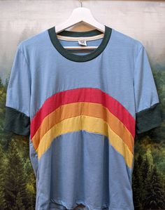 Santa Cruz Mountains Rainbow Camp Collection TShirt in Cloud Blue with Forest Green Accents This classic SCM design on a comfy classic shirt from Camp Collection: ∞Short sleeve crew neck ringer style tee, with long sleeves and shorter length ∞Rib neckband and sleeve bands ∞Slightly sheer vintage cloud blue jersey ∞Locker loop at back neck ∞60% cotton / 40% polyester ∞Fits true to size ∞Manufactured in the USA ∞Design by Present owner, Jackie Care - Machine wash cold, tumble dry low Casual Color Block Crew Neck T-shirt, Summer Color Block Crew Neck T-shirt, Retro Tri-blend Crew Neck T-shirt, Retro Style Blue T-shirt For Spring, Casual Green Color Block T-shirt, Casual Blue Color Block Shirt, Casual Crew Neck Color Block T-shirt, Casual Color Block Short Sleeve T-shirt, Color Block Relaxed Fit Tops For Everyday