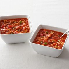 two white bowls filled with food on top of a table