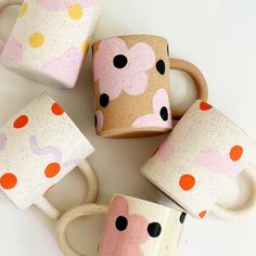 four coffee mugs decorated with polka dots and flowers on white background, top view