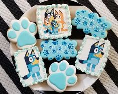 decorated cookies on a plate with paw prints and blue frosting for the dog's name